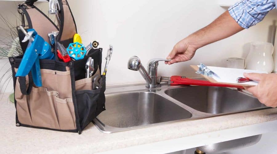 Emergency plumber repairing a leaking kitchen faucet - Licensed Plumber